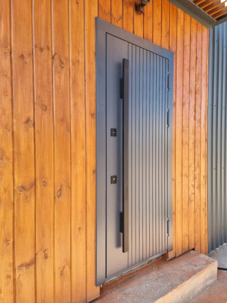 Входная термодверь с вертикальной  фрезеровкой снаружи и комбинированной панелью МДФ внутри.